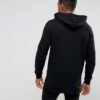 Black zip-up hoodie with custom logo option. Soft, textured fabric. Longline fit. Quality stitching detail evident. Perfect f