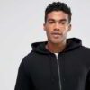 Black zip-up hoodie with custom logo option. Soft, textured fabric. Longline fit. Quality stitching detail evident. Perfect f