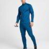 Running tracksuit with raglan sleeves, showing polyester texture. Partial zipper and visible stitching detail. Athletic wear.