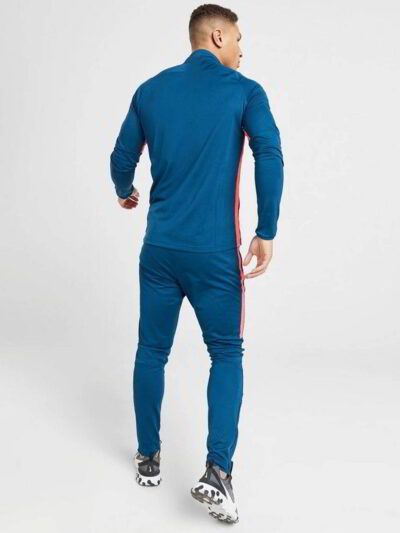 Running tracksuit with raglan sleeves, showing polyester texture. Partial zipper and visible stitching detail. Athletic wear.