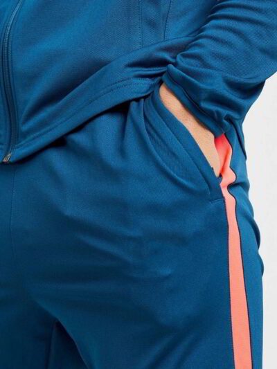 Running tracksuit with raglan sleeves, showing polyester texture. Partial zipper and visible stitching detail. Athletic wear.