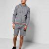 Sporty short tracksuit in bulk production. Ribbed knit trim, contrasting side stripes, close-up showing smooth, durable fabri