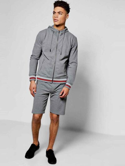 Sporty short tracksuit in bulk production. Ribbed knit trim, contrasting side stripes, close-up showing smooth, durable fabri