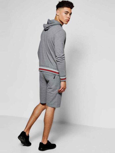 Sporty short tracksuit in bulk production. Ribbed knit trim, contrasting side stripes, close-up showing smooth, durable fabri
