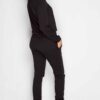 Black sweat suit with ripped knee detail, comfortable loungewear. Soft, textured fabric, visible stitching. Casual, stylish.