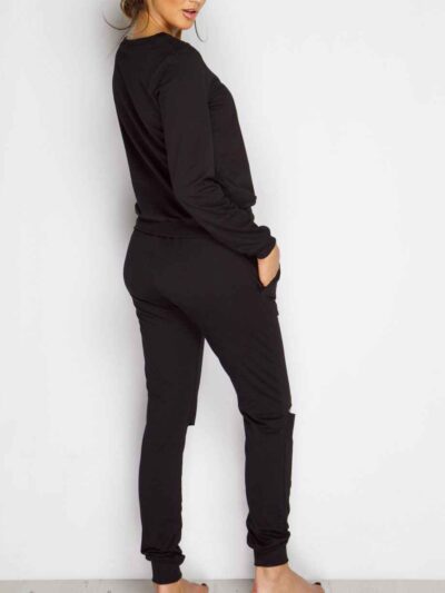 Black sweat suit with ripped knee detail, comfortable loungewear. Soft, textured fabric, visible stitching. Casual, stylish.