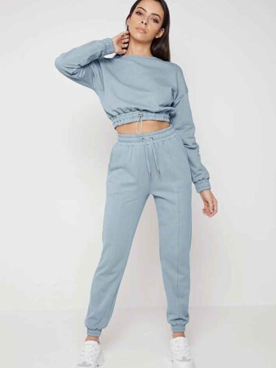 Woman in athletic tracksuit: heathered grey, comfy fit. Note the elastic cuffs, drawstring waist, and clean stitching. Active