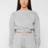 Woman in athletic tracksuit: heathered grey, comfy fit. Note the elastic cuffs, drawstring waist, and clean stitching. Active