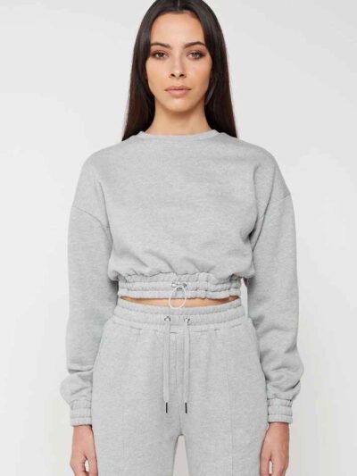 Woman in athletic tracksuit: heathered grey, comfy fit. Note the elastic cuffs, drawstring waist, and clean stitching. Active