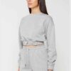 Woman in athletic tracksuit: heathered grey, comfy fit. Note the elastic cuffs, drawstring waist, and clean stitching. Active