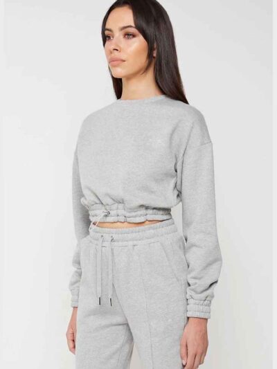 Woman in athletic tracksuit: heathered grey, comfy fit. Note the elastic cuffs, drawstring waist, and clean stitching. Active