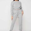 Woman in athletic tracksuit: heathered grey, comfy fit. Note the elastic cuffs, drawstring waist, and clean stitching. Active