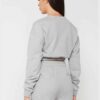 Woman in athletic tracksuit: heathered grey, comfy fit. Note the elastic cuffs, drawstring waist, and clean stitching. Active