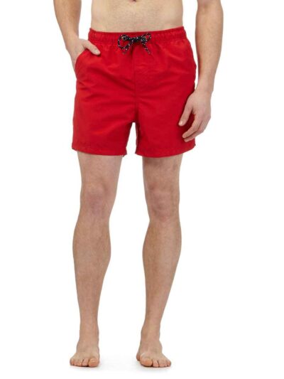 Lightweight summer beach shorts in a vibrant coral hue. Fine stitching detail shows durable construction. Soft, textured fabr