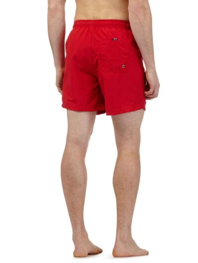 Lightweight summer beach shorts in a vibrant coral hue. Fine stitching detail shows durable construction. Soft, textured fabr