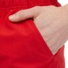 Lightweight summer beach shorts in a vibrant coral hue. Fine stitching detail shows durable construction. Soft, textured fabr