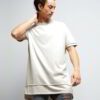 Stack of youth t-shirts. Soft cotton knit texture, clean seams. Various colors hinted: red, green, blue. Basic crewneck style
