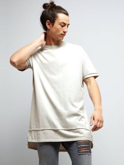 Stack of youth t-shirts. Soft cotton knit texture, clean seams. Various colors hinted: red, green, blue. Basic crewneck style