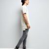 Stack of youth t-shirts. Soft cotton knit texture, clean seams. Various colors hinted: red, green, blue. Basic crewneck style