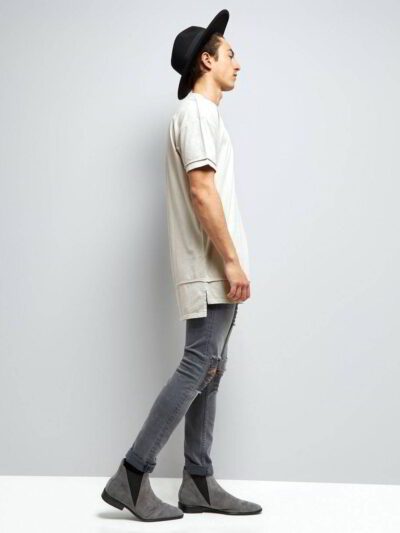 Stack of youth t-shirts. Soft cotton knit texture, clean seams. Various colors hinted: red, green, blue. Basic crewneck style