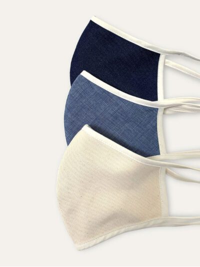 Close-up of a breathable cotton face mask. Soft fabric texture, neat stitching. Reusable face covering, light color, comforta