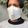 Close-up of a breathable cotton face mask. Soft fabric texture, neat stitching. Reusable face covering, light color, comforta