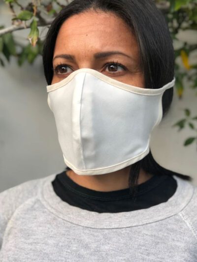 Close-up of a breathable cotton face mask. Soft fabric texture, neat stitching. Reusable face covering, light color, comforta