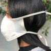 Close-up of a breathable cotton face mask. Soft fabric texture, neat stitching. Reusable face covering, light color, comforta