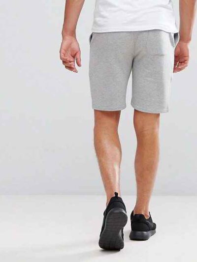 Athletic training shorts, close-up showing breathable woven fabric, reinforced stitching. Performance garment, likely navy or