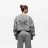Ladies' two-piece tracksuit in soft-focus, muted color. Hooded zip jacket & wide-leg pants. Visible subtle stitching detail.