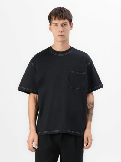 Black oversized t-shirt with contrast white stitching, drop shoulders, pocket. Soft, textured fabric. Custom logo imprint are