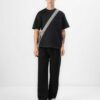 Black oversized t-shirt with contrast white stitching, drop shoulders, pocket. Soft, textured fabric. Custom logo imprint are