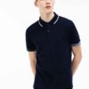 Close-up of a finely knit polo shirt, hints of navy and white. Sharp collar, clean stitching. Classic menswear garment detail
