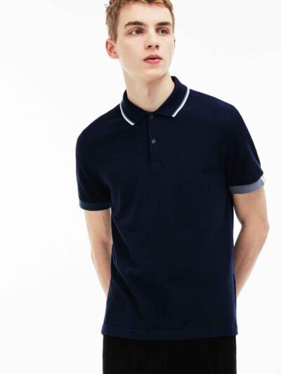 Close-up of a finely knit polo shirt, hints of navy and white. Sharp collar, clean stitching. Classic menswear garment detail