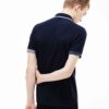 Close-up of a finely knit polo shirt, hints of navy and white. Sharp collar, clean stitching. Classic menswear garment detail