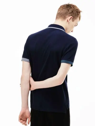 Close-up of a finely knit polo shirt, hints of navy and white. Sharp collar, clean stitching. Classic menswear garment detail