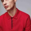 Close-up of a navy polo. Fine pique knit texture, crisp collar, clean three-button placket with reinforced stitching. Ideal g
