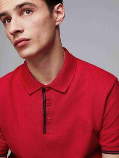 Close-up of a navy polo. Fine pique knit texture, crisp collar, clean three-button placket with reinforced stitching. Ideal g