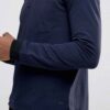 Close-up of a textured performance polo shirt. Fine stitching detail, breathable moisture-wicking fabric, a subtle blue hue.