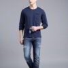 Close-up of a navy blue t-shirt with a white logo print. Cotton fabric texture, clean stitching detail. Short sleeve crew nec