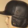Leather driving cap with plush fleece lining. Warm winter hat, flat style, ear flaps. Fine stitching detail visible on smooth
