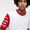 Men's crewneck tee showing custom design area. Soft cotton texture, reinforced stitching. Solid color backdrop highlights per