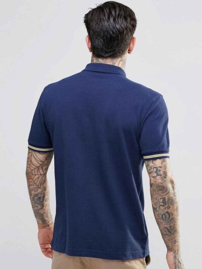 Close-up: Navy blue men's polo shirt. Soft pique knit texture, clean stitching. Classic short sleeves, subtle collar, custom