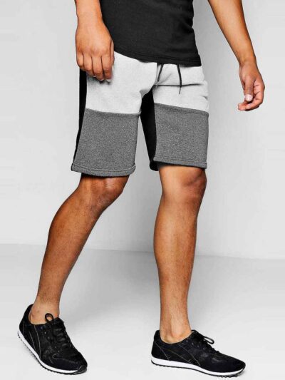 Close-up of charcoal sweat shorts featuring a raised, detailed embroidered logo. Soft, looped-back cotton fabric. Premium sti