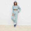Women's running tracksuit set. Close-up on soft, slightly textured fabric. Zip-up jacket with pink trim. Comfortable fit for