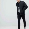 Black and grey crew neck sweatshirt, ribbed knit texture, patch detail. Relaxed fit, visible stitching, ideal for layering. -
