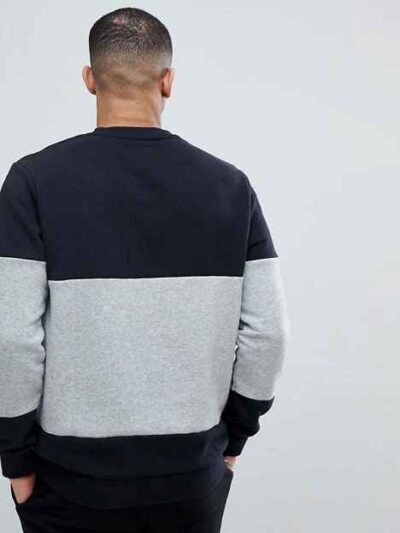 Black and grey crew neck sweatshirt, ribbed knit texture, patch detail. Relaxed fit, visible stitching, ideal for layering. -