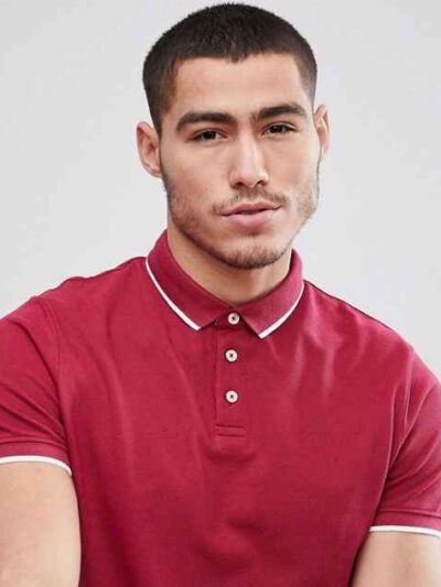 Close-up of a navy polo shirt. Fine-knit cotton with crisp collar, meticulously stitched placket, and subtle texture. Uniform