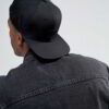 Structured canvas snapback cap. Flat brim, visible stitching detail. Adjustable back closure. Modern streetwear style. - View