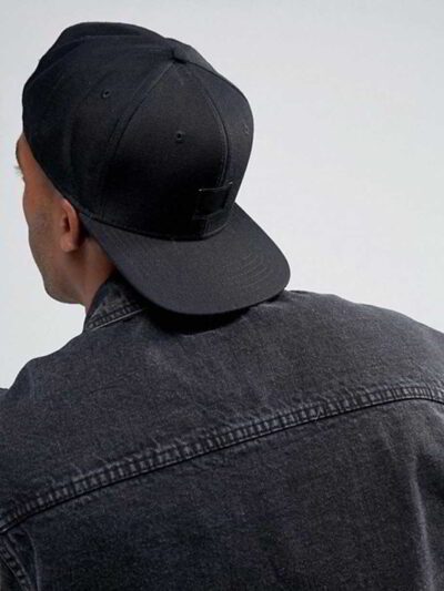 Structured canvas snapback cap. Flat brim, visible stitching detail. Adjustable back closure. Modern streetwear style. - View
